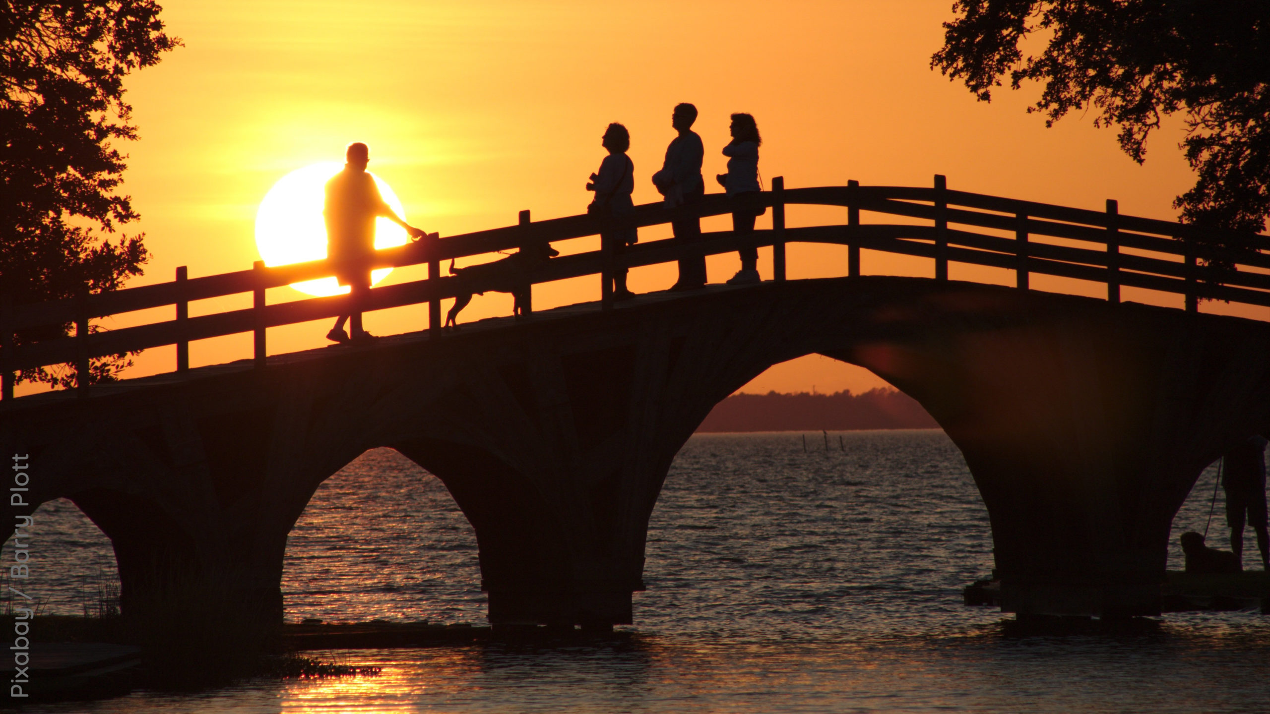 Abendhimmel mit Sonnenuntergang, Menschen auf einer Brücke über das Wasser